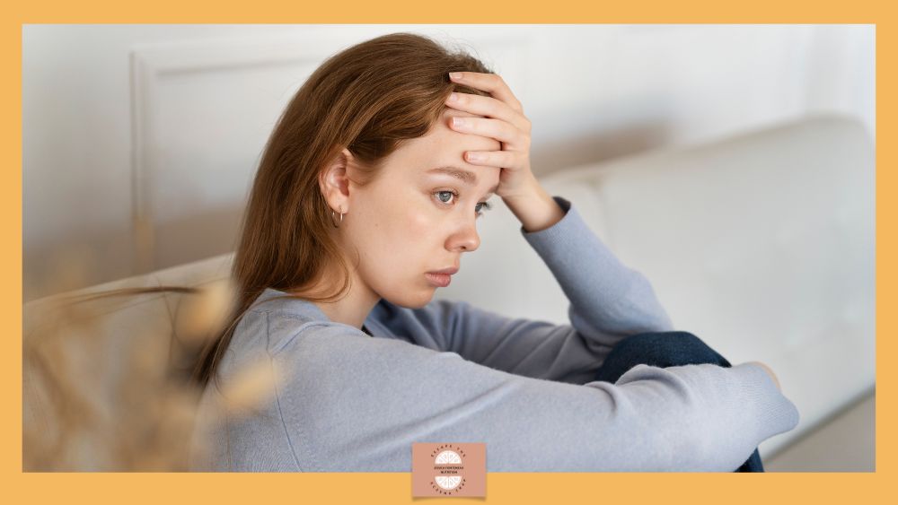 How to Calm a Stress Triggered Painful Eczema Flare - young woman with long dark hair holds head in hand, looking unhappy