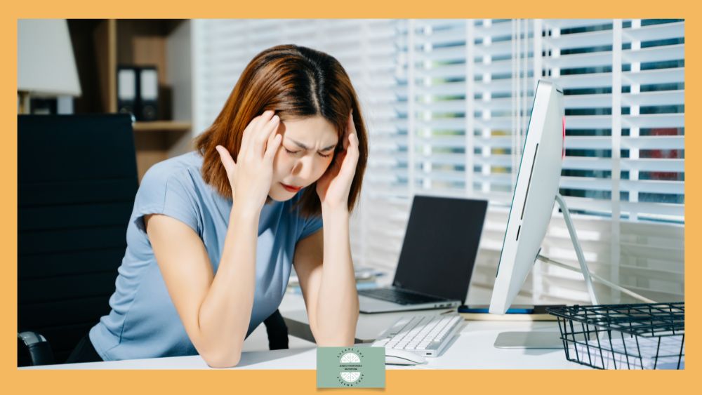 Adult Onset Eczema: A Growing Phenomenon in Adulthood - woman at desk with head in hands, stressed.