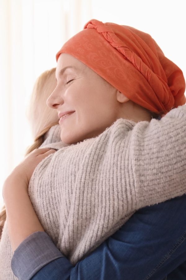 Cancer Prevention and support - image of two women hugging, one with an orange headscarf.